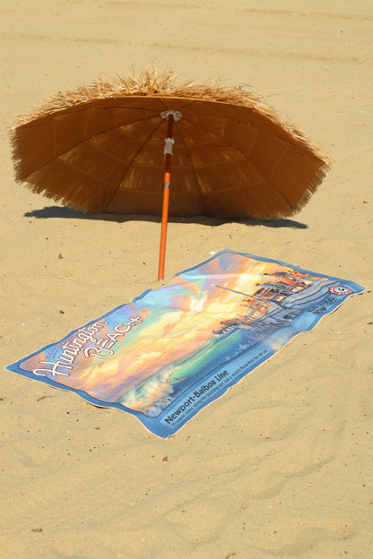 Huntington Beach vintage travel poster beach towel laying on the beach under a tiki umbrella