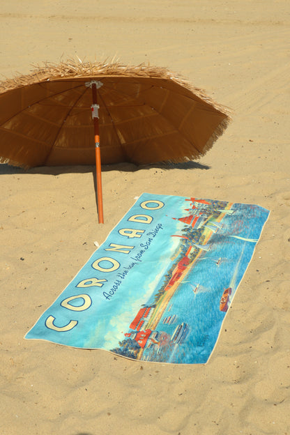Coronado vintage travel poster beach towel laying in the sand under a tiki umbrella