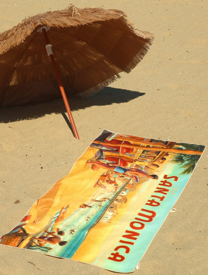 Santa Monica vintage travel poster beach towel on sand under tiki umbrella
